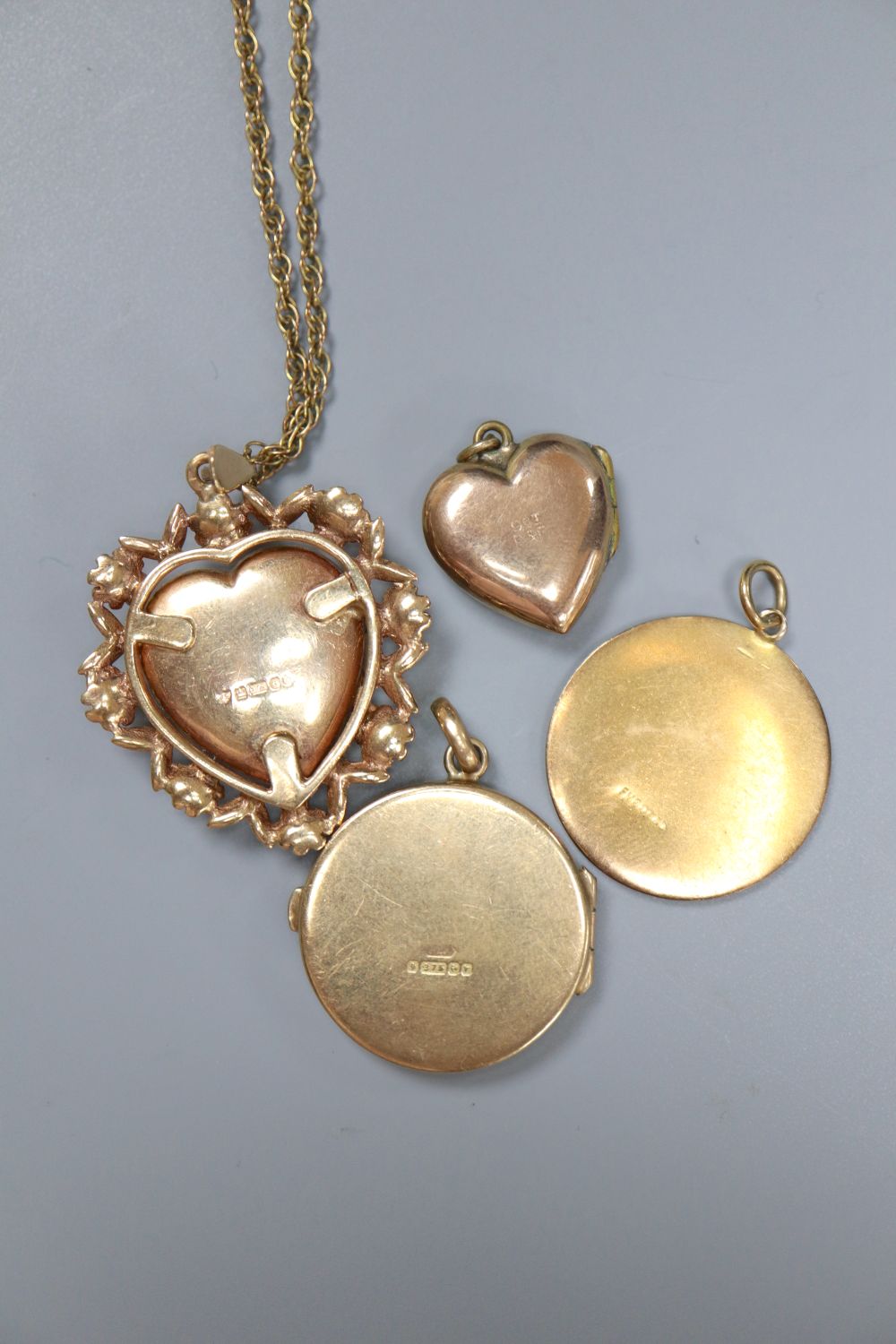 A 9ct gold heart-shaped fancy locket on chain, an engraved circular locket, a small heart-shaped locket and a St Christopher medallion